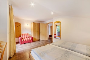 A bedroom with a bed, a red and white striped chair, wooden wardrobes, and a window with a view.