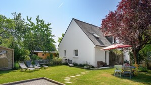 A white house with a sloped roof, a gravel patio, and a small garden with a red umbrella. - Holiday Home 'La Fleur De Vie' with Private Garden and Wi-Fi (Pluneret)