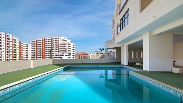 A rooftop pool with a clear view of surrounding high-rise buildings. - Apartment 'Seaside  - Praia Da Rocha' with Mountain View, Shared Pool and Wi-Fi (Portimão)