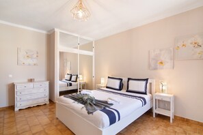 A bedroom with a bed, bedside tables, a dresser, and artwork on the walls.