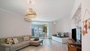 A modern living room with a sofa, a television, and a wooden entertainment unit.