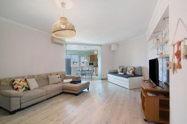 A modern living room with a sofa, a television, and a wooden entertainment unit.