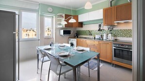 A modern kitchen with a dining table set for two, a microwave, oven, and a view of the city through the window.