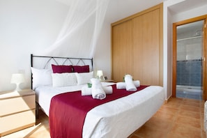 A hotel room with a bed, a nightstand, a wooden wardrobe, and a shower area.