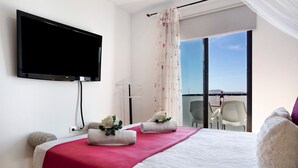 Une chambre d’hôtel comprenant un lit, un téléviseur à écran plat, un balcon avec vue et une chaise.