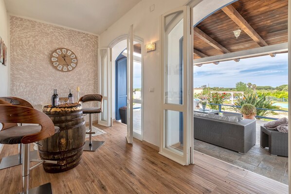 A room with a wooden barrel, a clock, and a view to an outdoor seating area. - 'Villa Sara' with Private Pool, Wi-Fi and Air Conditioning (Sorso)