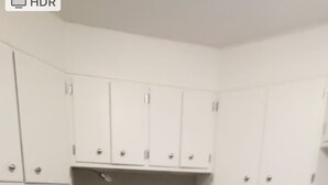 A compact kitchen with white cabinets, a microwave, a coffee maker, and a dishwasher.