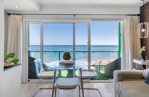 Een balkon met een glazen tafel en stoelen, een bank en uitzicht op zee.