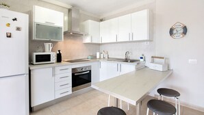 Una cocina moderna con armarios blancos, microondas, estufa y fregadero.