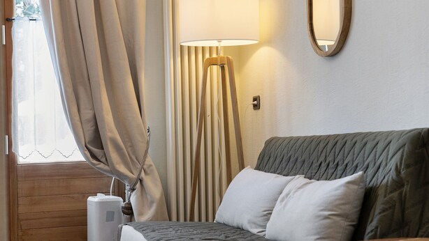 Une chambre à coucher avec un lit, une lampe sur pied, des rideaux et une fenêtre.