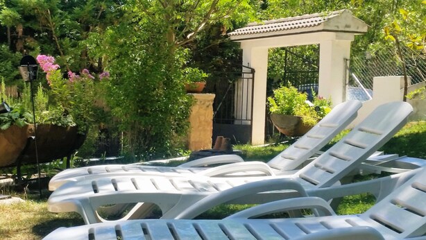 White plastic lounge chairs arranged outdoors, a white gazebo, and potted plants. - Country House 'El Rincón De Gredos' with Mountain Views by the River – Cozy Retreat (Navaluenga)