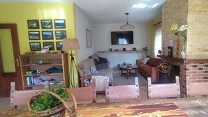 A living room with a sofa, a coffee table, a fireplace, a television, and a bookshelf. - Country House 'El Rincón De Gredos' with Mountain Views by the River – Cozy Retreat (Navaluenga)