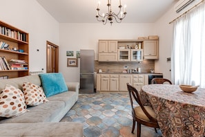 Une cuisine moderne dotée d’un réfrigérateur encastré, de meubles de rangement en bois et d’un coin repas agrémenté d’une nappe à motifs.
