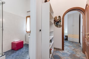 Une salle de bain avec une douche, une boîte de rangement rouge et un radiateur blanc.