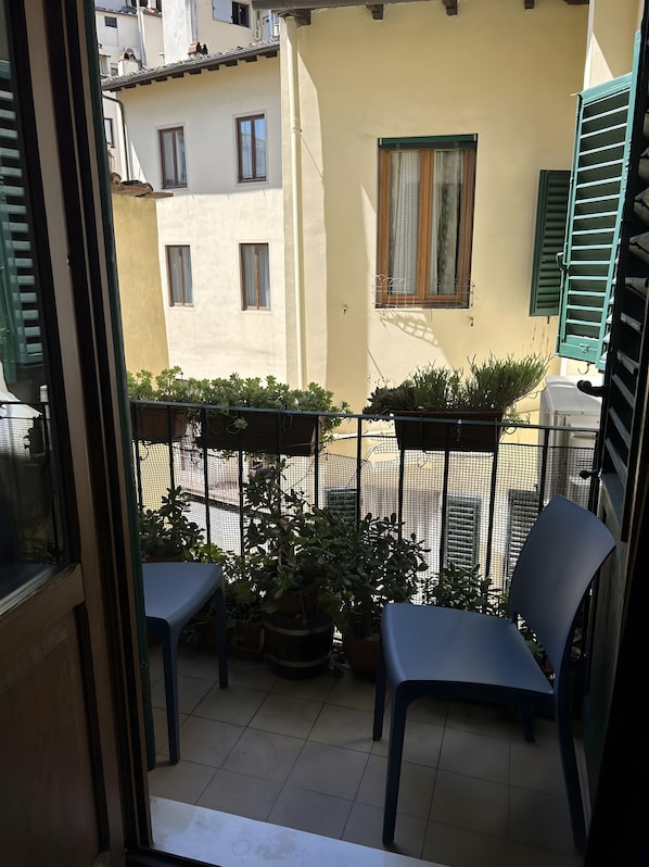 Un balcon avec deux chaises, une table et des plantes en pot.