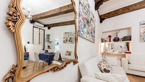 A room with a large ornate mirror, white sofas, a wooden ceiling, and abstract art on the walls.
