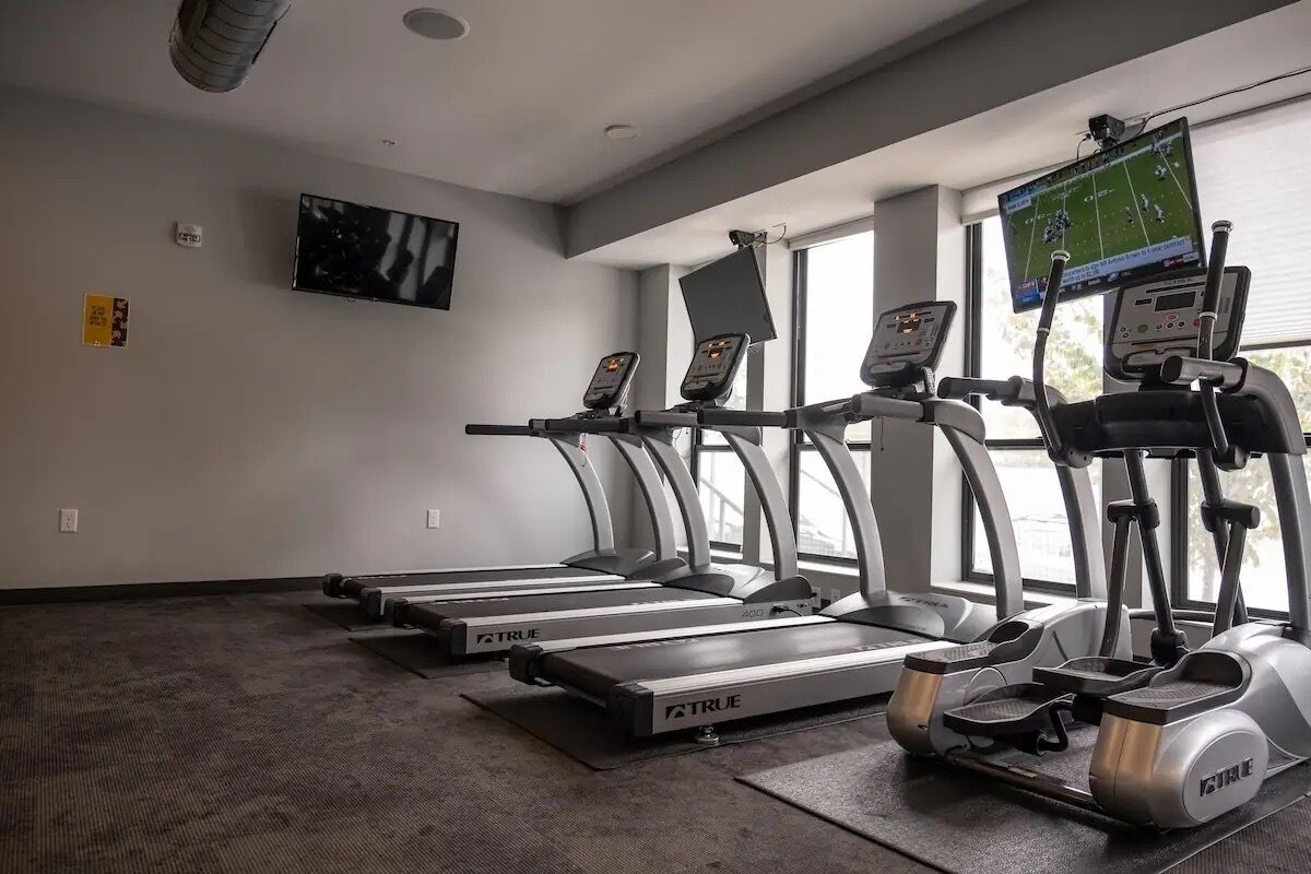 A gym with treadmills, a TV, and a window.