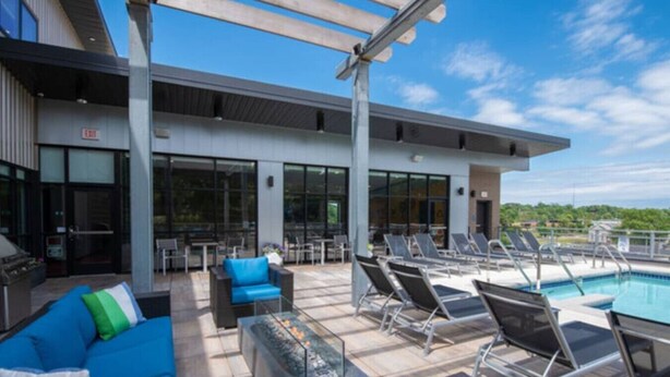 Un espace piscine aménagé sur le toit, avec des chaises longues, un canapé bleu et une table en verre.