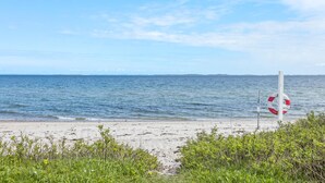 Une plage avec un panneau indiquant la présence d’une bouée de sauvetage et une vue dégagée sur la mer.