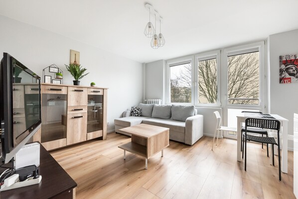 Relax in this stylish living room with a large window offering a view of the outdoors, a comfortable sofa, and a dining area.