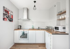 Prepare meals in the kitchen with a stainless steel range hood and microwave, complemented by a pendant light.