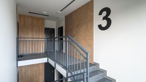 A modern staircase with a metal railing, a wooden panel wall, and a large number '3' on the right.