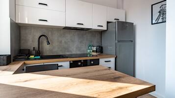 Een moderne keuken met witte kastjes, een zwarte kraan, een roestvrijstalen koelkast en een houten aanrecht.