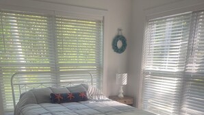 A bedroom with a bed, a nightstand, a lamp, and a wreath on the wall.