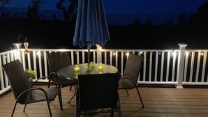 A deck with a round table, chairs, and string lights.