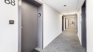 A long, narrow hallway with a carpeted floor, doors on both sides, and a number '88' on the left wall.