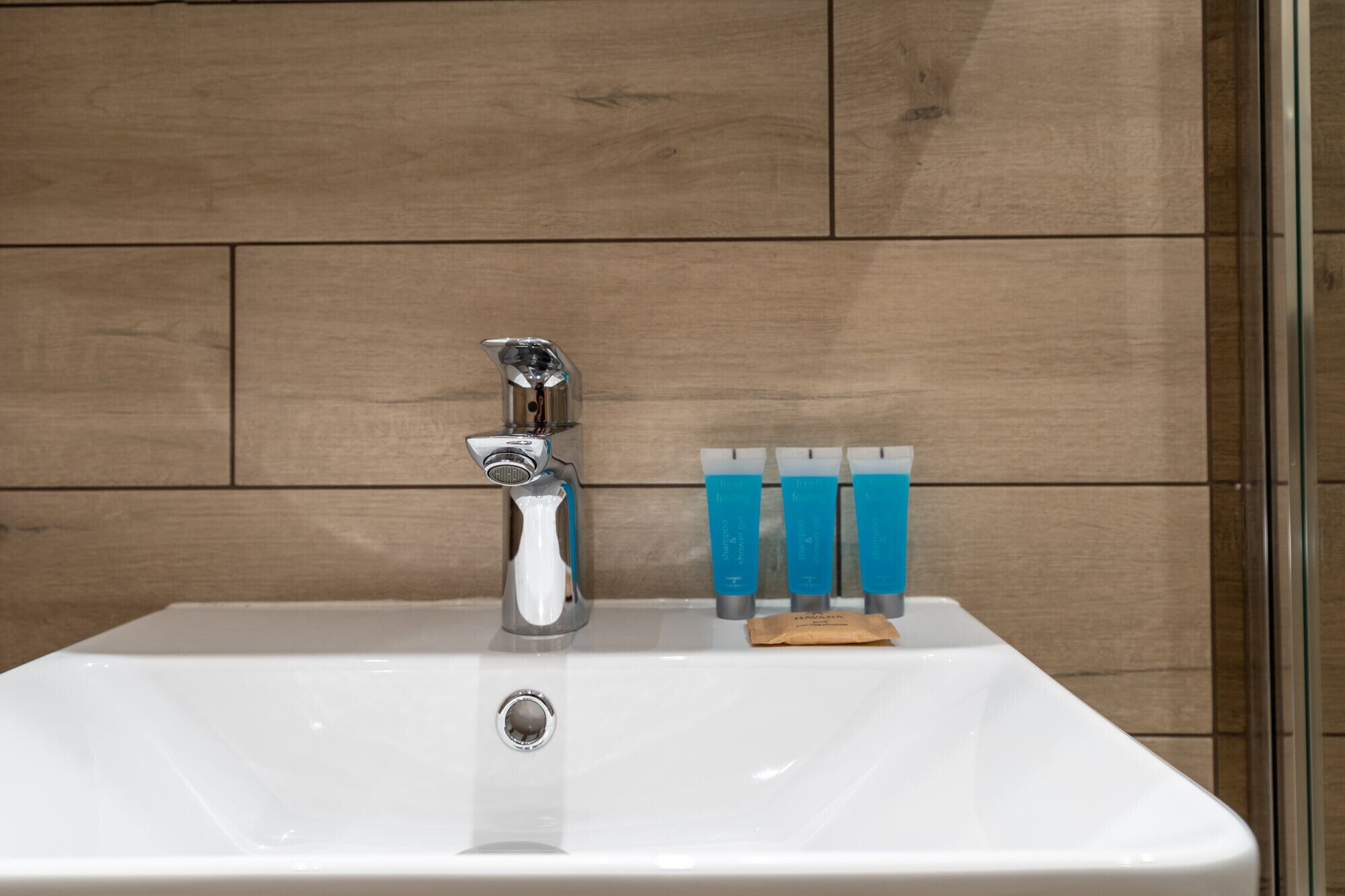 Un lavabo de salle de bain avec un robinet chromé et trois tubes de dentifrice bleus.