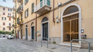 Una calle empedrada con un edificio que tiene ventanas en arco y una barandilla de metal.