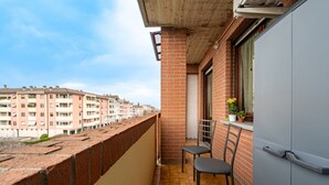 A balcony with a brick wall, two chairs, a window with a view of other buildings, and a grey cabinet. - GuestHost - Comfortable apartment located on the third and last floor of a building with a lift (suitable for disabled people).In 85 m2 of space it comfortably accommodates five people, a double bedroom and a bedroom with a single bed, a sofa bed in the  (Parma)