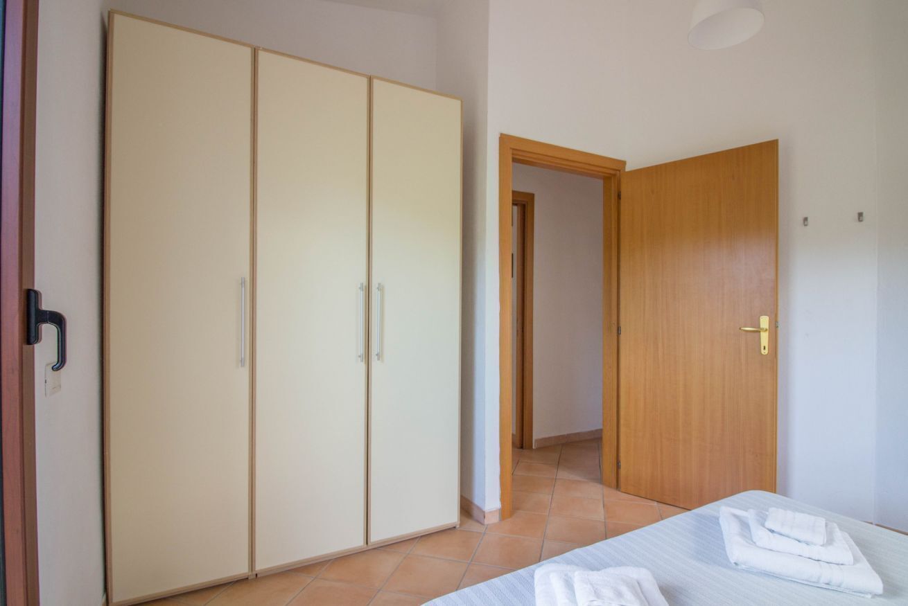 A bedroom with a bed, a wardrobe, and a door leading to another room.