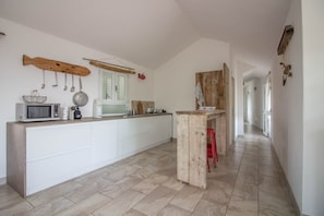 A kitchen with a wooden fish decoration, a microwave, and a kettle on the counter.