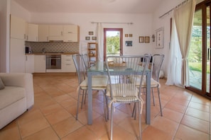 Une cuisine moderne avec des meubles blancs, une table à manger avec des chaises en métal et un canapé.