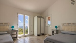 Un dormitorio con dos camas, un armario, una ventana con vistas y una puerta que da a un espacio exterior.