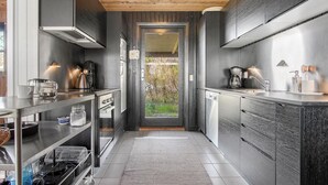 A modern kitchen with stainless steel appliances, a coffee maker, and a view through the door. - 4 bedroom pet friendly home in Strandby (Strandby)
