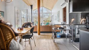A modern kitchen with a large island, wooden flooring, and a view through large windows. - 4 bedroom pet friendly home in Strandby (Strandby)