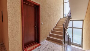 Una escalera con una puerta de madera y un felpudo rojo que lleva a una habitación con piso de piedra.