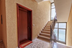 Una escalera con una puerta de madera y un felpudo rojo que lleva a una habitación con piso de piedra.