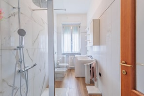 A modern bathroom with a shower, toilet, bidet, and sink.