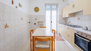 Una cocina con una mesa de comedor, sillas, estufa, horno y alacenas.
