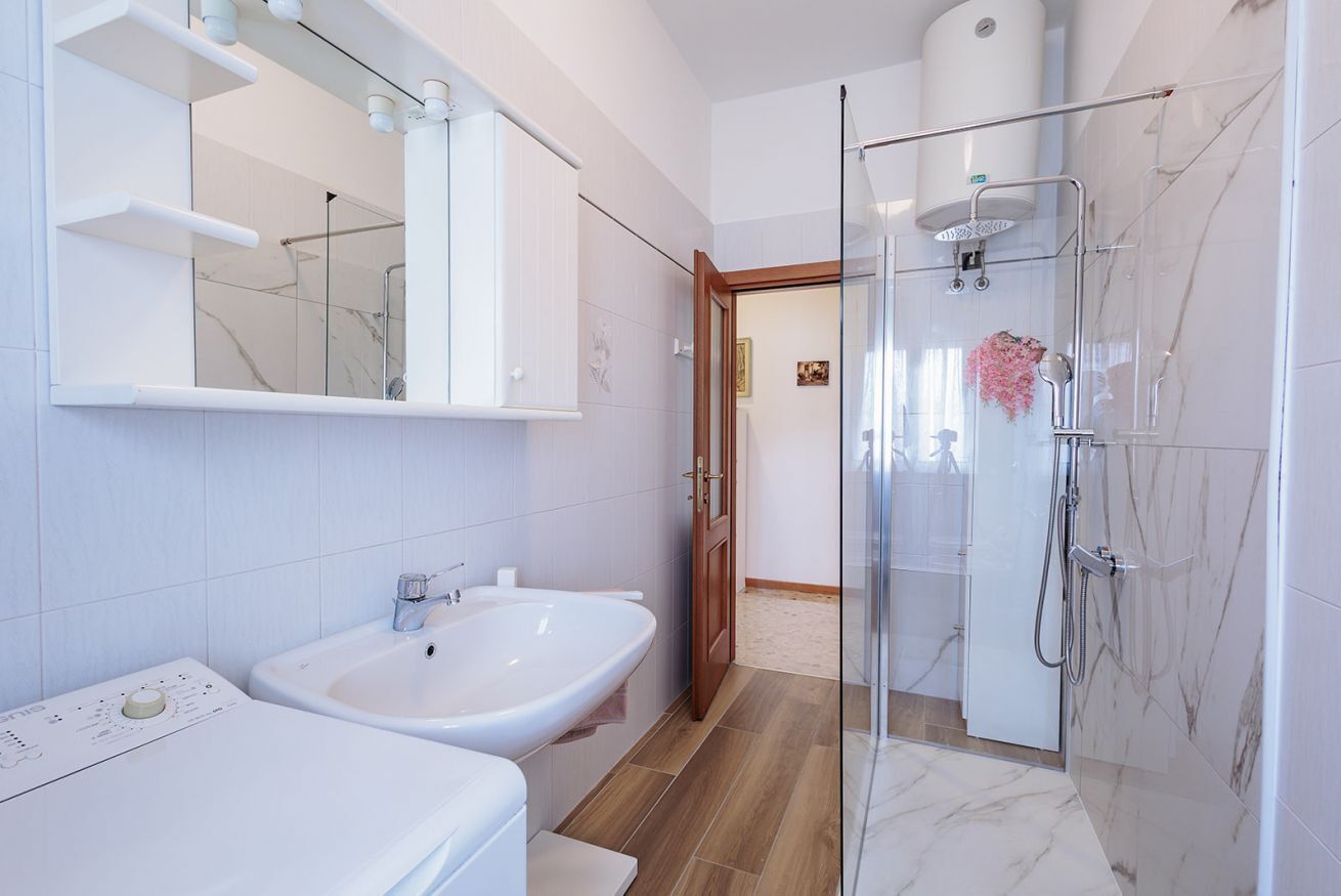 Un baño con cabina de ducha de vidrio, lavamanos doble y un espejo grande.