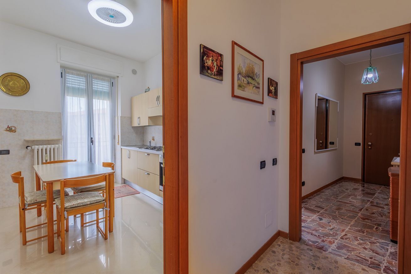 Un pasillo bien iluminado con comedor, cocina y una puerta que da a otra habitación.