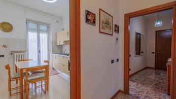 Un pasillo bien iluminado con comedor, cocina y una puerta que da a otra habitación.