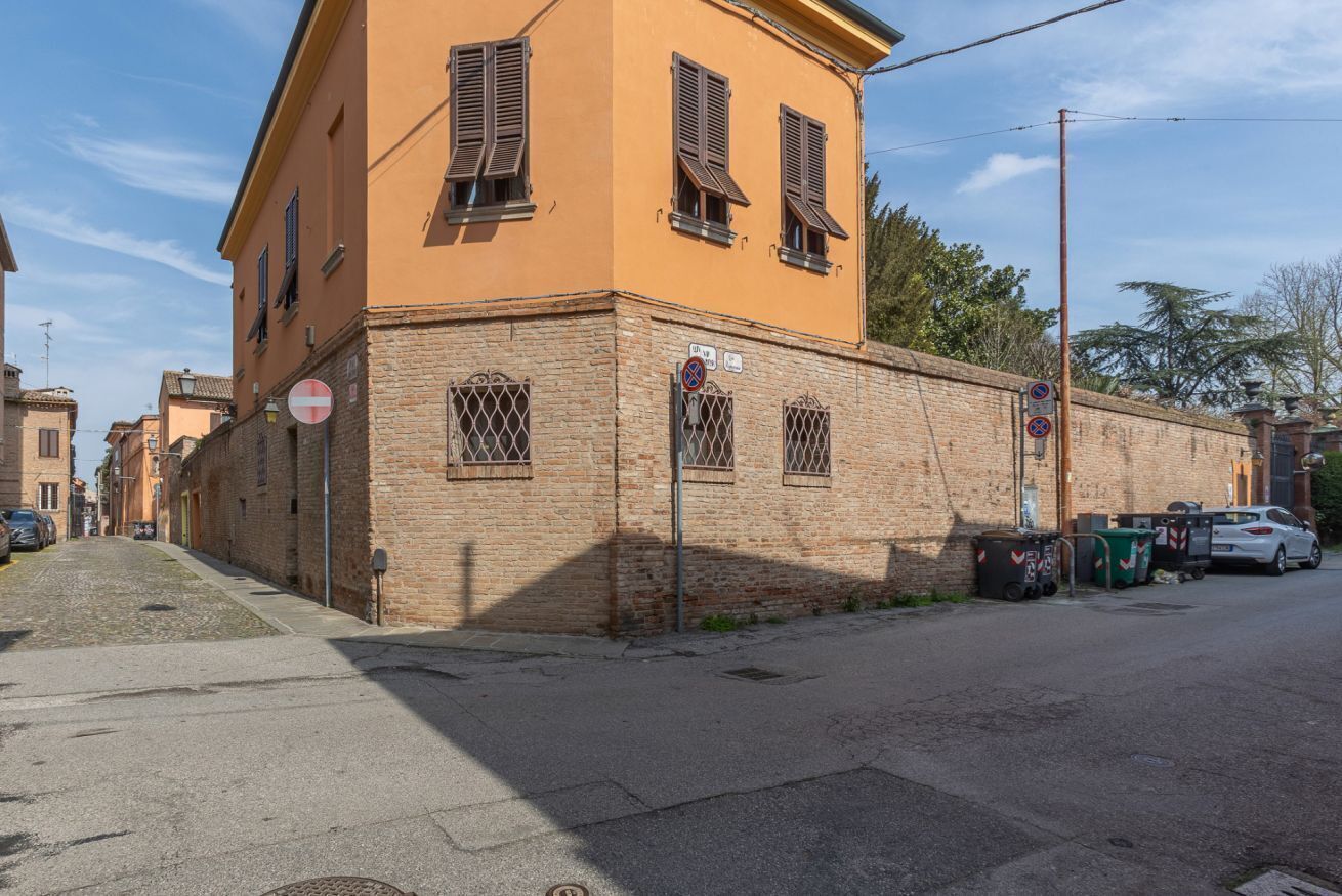A building with a brick facade, shuttered windows, and a no parking sign.
