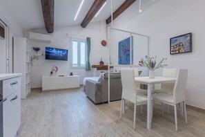 A modern living room with a sofa, dining table, and TV.