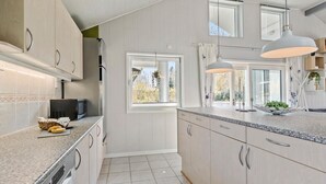 Une cuisine moderne avec des meubles en bois clair, un plan de travail en granit et des luminaires suspendus.