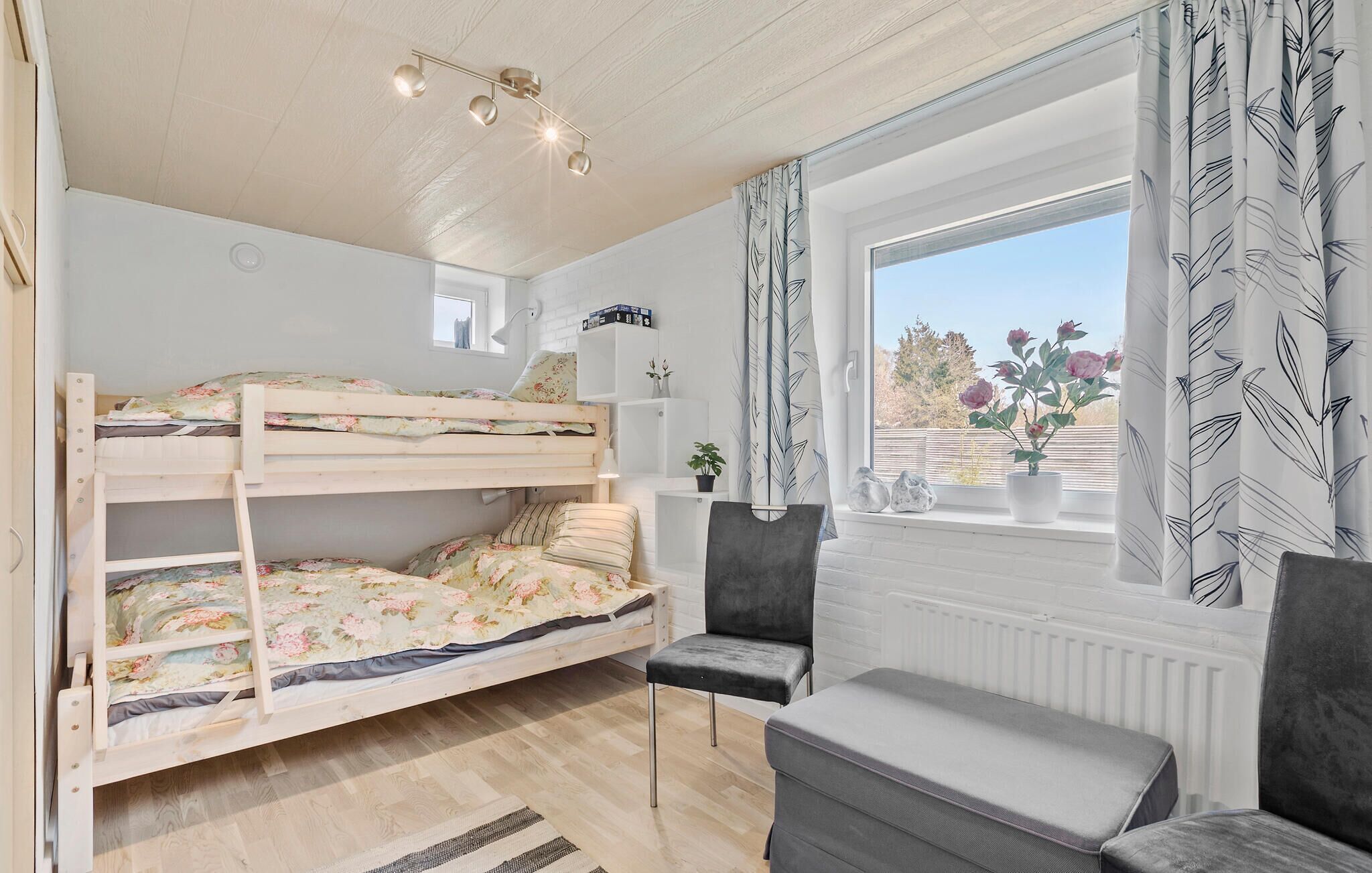 Een slaapkamer met een stapelbed, een raam, een bureau en een stoel.